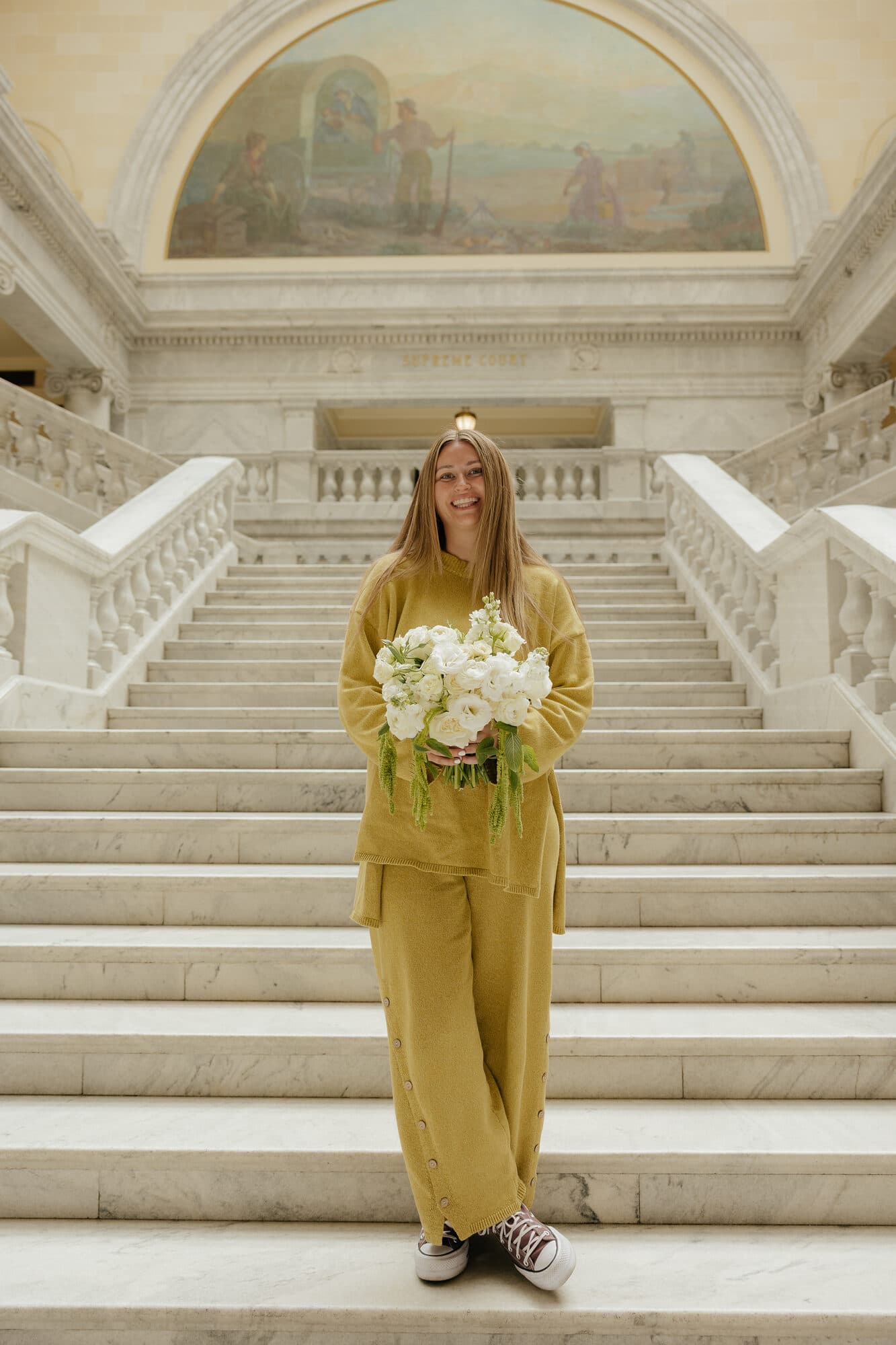 Clipped Florals owner smiling on the steps of the Utah State Capitol, holding a white bouquet
